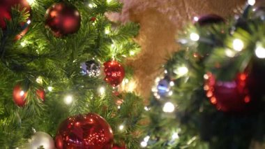 Neşeli Açık Hava Noel Ağacı 'nın yakın çekimleri. Peri arka planında parlak kırmızı toplar var. Odaklanmamış çelenk ışıkları, Bokeh etkisi. Mutlu Noeller ve Mutlu Noeller konsepti.