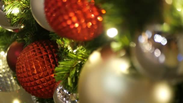 Primer plano del árbol de Navidad al aire libre decorado festivamente con bolas de color rojo brillante sobre el fondo borroso brillante hada. Luces de guirnalda desenfocadas, efecto Bokeh. Feliz Navidad y Felices Fiestas concepto. — Vídeo de stock