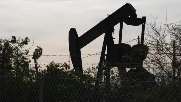 Paysage urbain industriel. La Brea Inglewood à Los Angeles. Prise de pompe de puits fonctionnant derrière la clôture. Extrait de forage de pétrole brut. Machine d'extraction d'huile avec piston de travail. Industrie pétrolière et gazière — Video