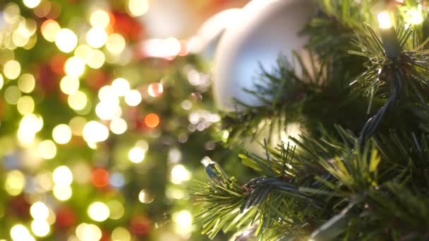 화려하게 장식 된 옥외 크리스마스 트리와 뿌연 반짝이는 요정 배경에 밝은 붉은 공이 있는 클로즈업. ( 영어 ) Defocused garland lights, Bokeh effect. 메리 크리스마스, 해피 홀리데이 컨셉트. — 비디오