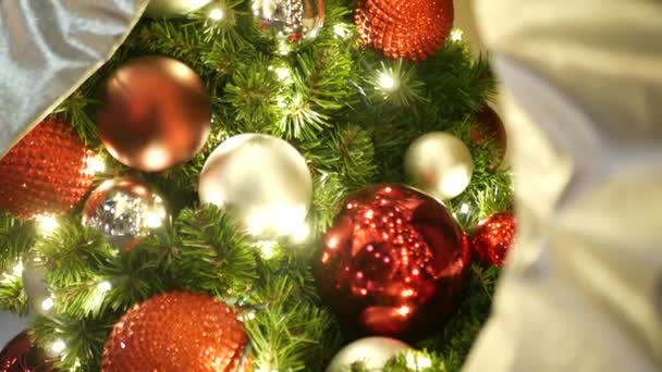 Крупный план празднично украшенной наружной елки с ярко-красными шариками на размытом блестящем фоне феи. Обезжиренные гирлянды, эффект Боке. Концепция "С Рождеством и счастливыми праздниками". — стоковое видео