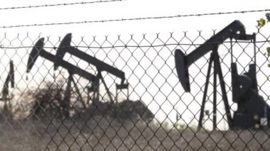 Endüstriyel şehir manzarası. La Brea Inglewood, Los Angeles 'ta. Çitin arkasında Jack 'i pompala. Sondaj kulesi ham petrol çıkarıyor. Çalışan pistonlu bir yağ makinası. Petrol ve doğalgaz endüstrisi