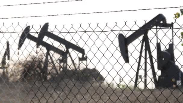 Paisagem urbana industrial. La Brea Inglewood em Los Angeles. Bem bombear jack operando atrás da cerca. Equipamento de perfuração extrair petróleo bruto. Máquina de mineração de óleo com pistão de trabalho. Indústria do petróleo e do gás — Vídeo de Stock