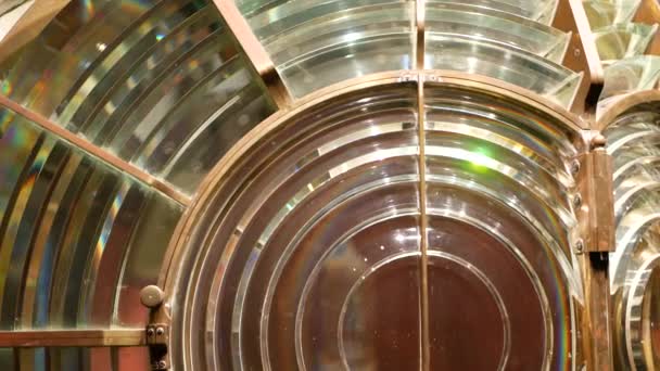 Fresnel lens with brass structure, nautical lighthouse tower. Detail of the glass lantern with rainbow spectrum. System of lamps and lenses to serve as a navigational aid. Old sea searchlight beacon. — Stock Video