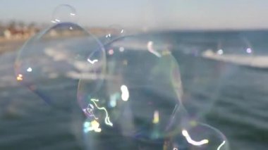 Kaliforniya 'da okyanus rıhtımında sabun köpüğü üflemek, yaz arkaplanını bulanıklaştırmak. Yaratıcı romantik metafor, hayal kurmak mutluluk ve sihir. Çocukluğun soyut sembolü, fantezi, özgürlük