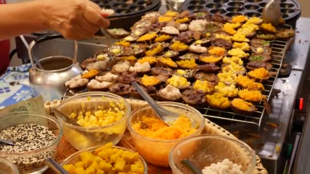 Exotische Oosterse Aziatische zoete heerlijke desserts, ongewone kleurrijke traditionele gerechten op de toonbanken van een bazar met straatvoedsel. Avond food court in bangkok, de hoofdstad van het koken. Nachtmarkt. — Stockvideo