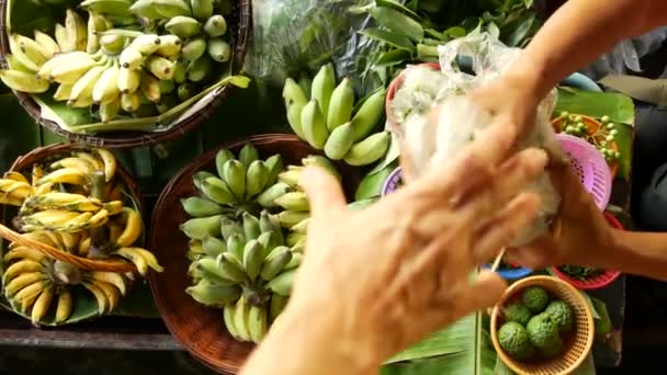 Iconic asian Lat Mayom floating market. Khlong river canal, long-tail boat with tropical exotic colorful fruits, organic locally grown vegetables. Top view of harvest and street food in wooden canoe — Stock Video