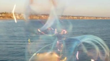 Kaliforniya 'da okyanus rıhtımında sabun köpüğü üflemek, yaz arkaplanını bulanıklaştırmak. Yaratıcı romantik metafor, hayal kurmak mutluluk ve sihir. Çocukluğun soyut sembolü, fantezi, özgürlük