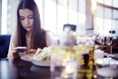café'de telefon kullanan genç kadın