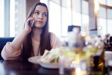 café'de telefon kullanan genç kadın
