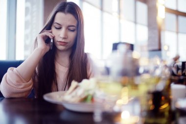 café'de telefon kullanan genç kadın