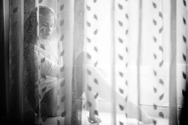Mujer joven sentada en el alféizar de la ventana — Foto de Stock