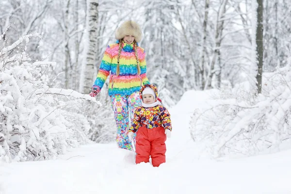 Flicka med mor i snöig park — Stockfoto