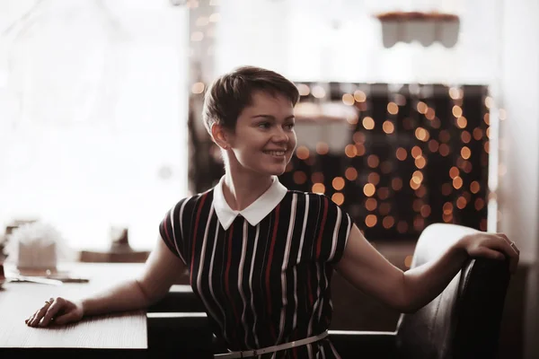 Korthårig flicka sitter på ett café — Stockfoto