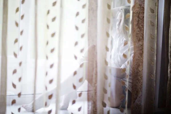 Young woman sitting on windowsill — Stock Photo, Image