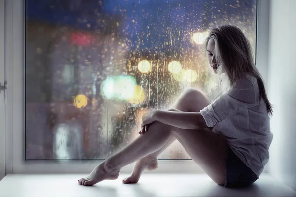 Sad girl sitting on windowsill — Stock Photo, Image