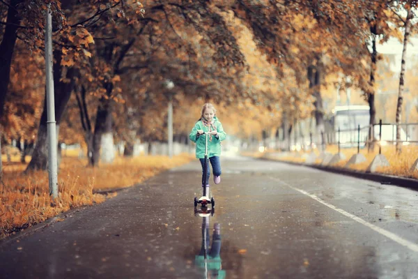 Flicka rider på skoter i park — Stockfoto