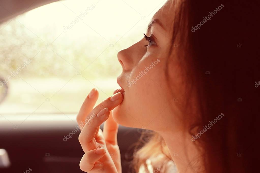 Girl painting lips in the car