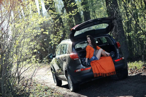 Kvinna sitter i bagageluckan på bilen — Stockfoto