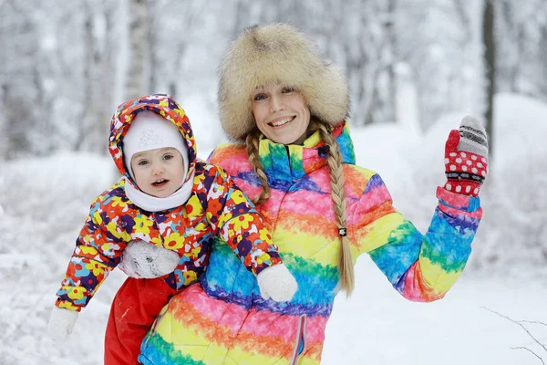 Flicka med mor i snöig park — Stockfoto