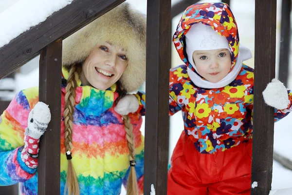 Flicka med mor i snöig park — Stockfoto