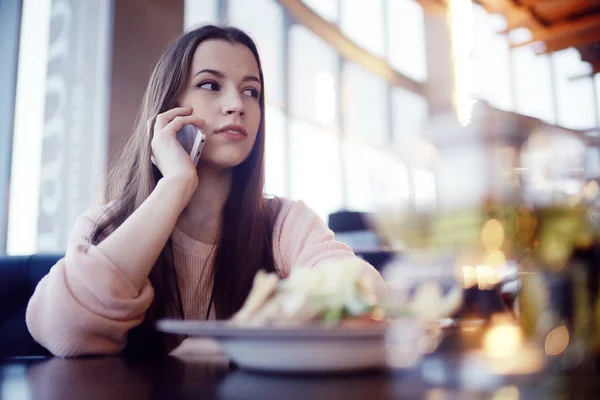 Młoda kobieta przy użyciu telefonu w kawiarni — Zdjęcie stockowe