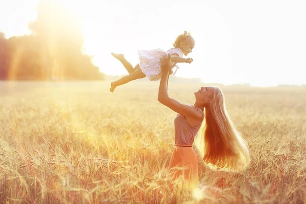 Mamma kastar upp en dotter i ett fält — Stockfoto