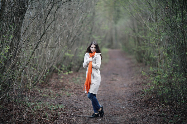 Young beautiful woman in white coat walking in spring forest