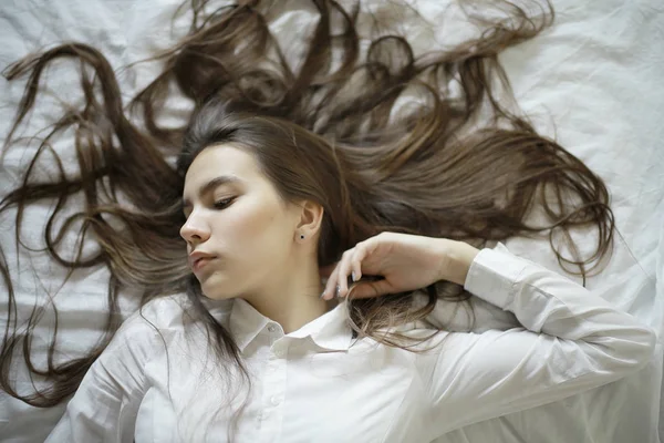Tonårig flicka med långt hår i sängen — Stockfoto