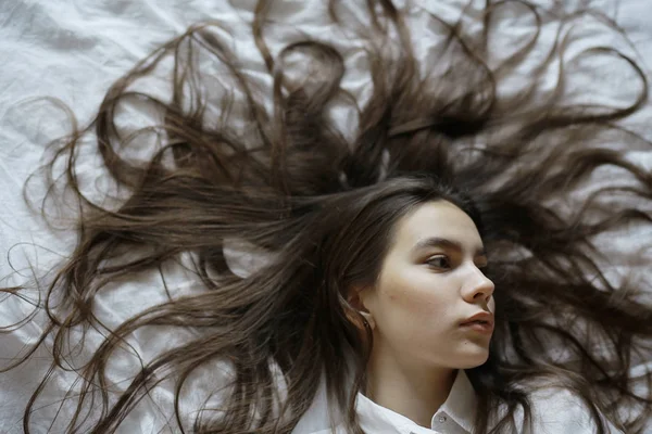 Adolescente com cabelos longos na cama — Fotografia de Stock