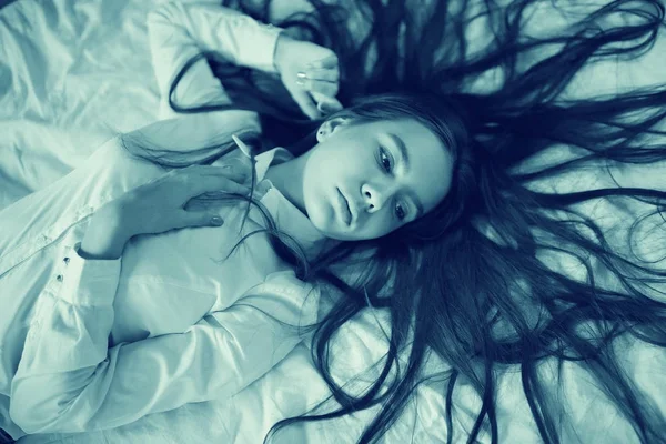 Adolescente com cabelos longos na cama — Fotografia de Stock