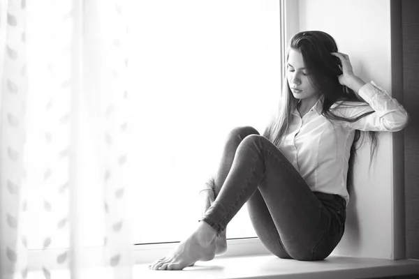 Teenage girl sitting on windowsill — Stock Photo, Image