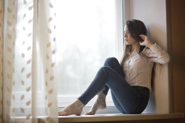 Teenage girl sitting on windowsill — Stock Photo, Image