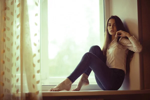 Teenage girl sitting on windowsill — Stock Photo, Image