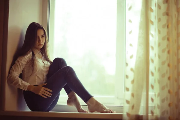 Teenage girl sitting on windowsill — Stock Photo, Image