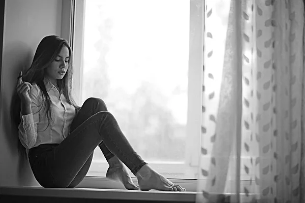 Pencere kenarında oturan genç kız — Stok fotoğraf