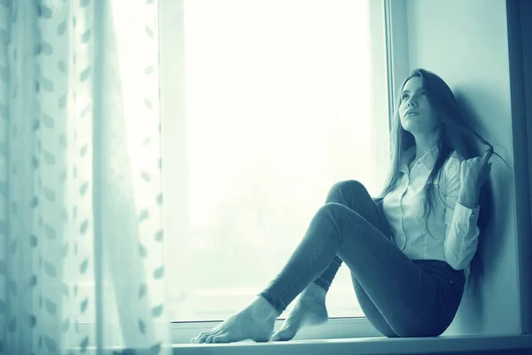 Teenage girl sitting on windowsill — Stock Photo, Image