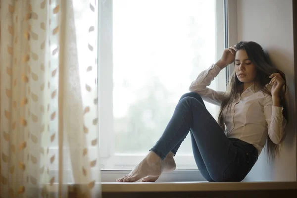 Pencere kenarında oturan genç kız — Stok fotoğraf