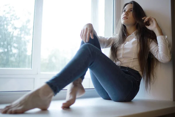 Teenage girl sitting on windowsill — Stock Photo, Image