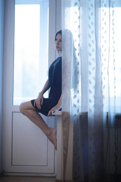 Sad teenage girl sitting on windowsill — Stock Photo, Image