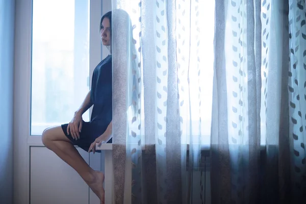 Sad teenage girl sitting on windowsill — Stock Photo, Image