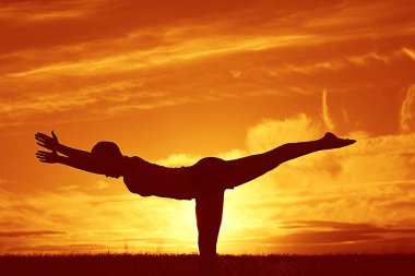 günbatımı gökyüzü karşı yoga yaparken kadın