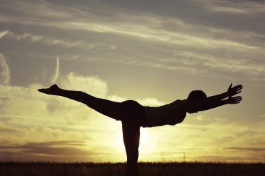 günbatımı gökyüzü karşı yoga yaparken kadın