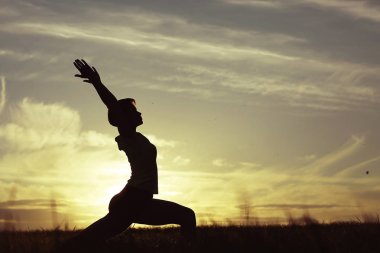 günbatımı gökyüzü karşı yoga yaparken kadın