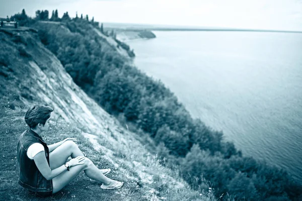Kobieta siedzi na brzegu rzeki — Zdjęcie stockowe
