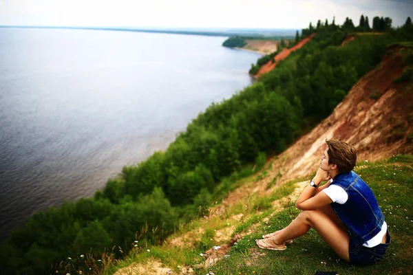 Žena sedí na břehu řeky — Stock fotografie