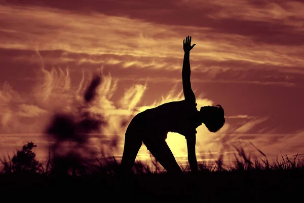 Mujer haciendo yoga contra la puesta del sol cielo — Foto de Stock