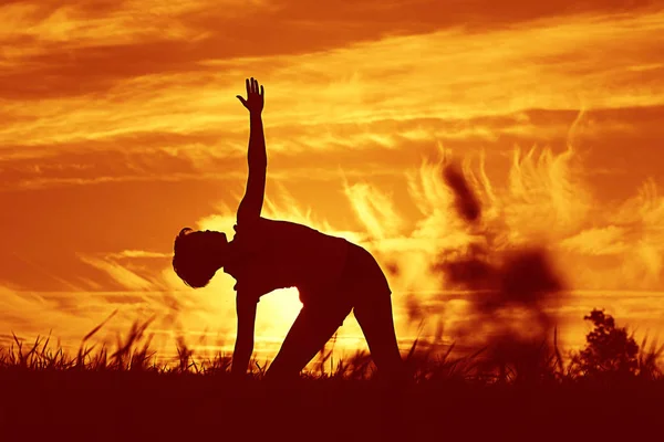 Femme faire du yoga contre le coucher du soleil ciel — Photo