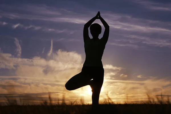 Mujer haciendo yoga contra la puesta del sol cielo — Foto de Stock