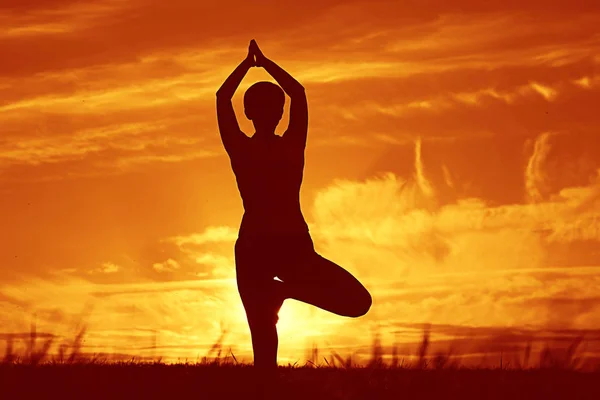 Mujer haciendo yoga contra la puesta del sol cielo —  Fotos de Stock